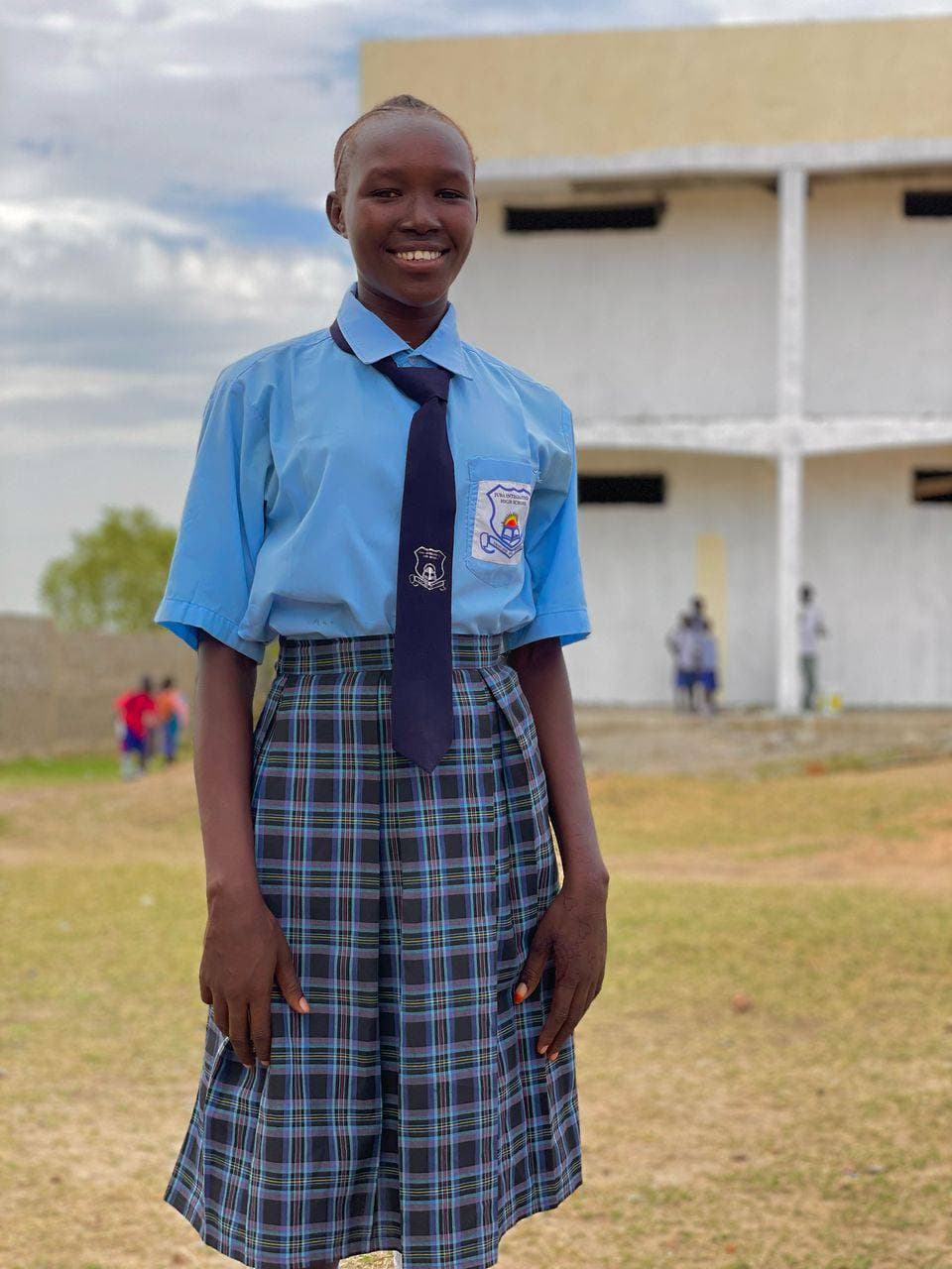 A girl in Juba Integrated High blue uniform smiling